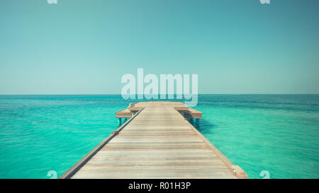 Beautiful beach with water bungalows and long jetty at Maldives. Summer travel holiday concept. Inspirational sea view, sky and endless wooden pier Stock Photo