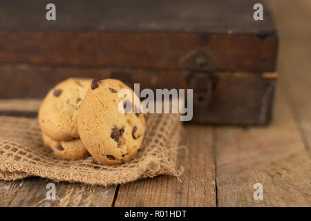 Cookies tied with a gray jute string into a bow. Cookies of sweets on a wooden kitchen table. Black background. Stock Photo