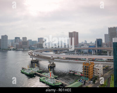 Modern highway with automobiles and train leading to a bridge. Rainbow bridge, Tokyo, Japan. Stock Photo