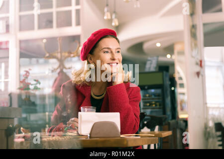 Elegant woman feeling amazing sitting in bakery and looking into window Stock Photo