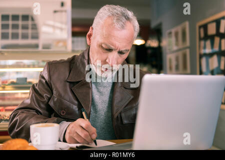 Famous inspired writer holding pencil while making notes to novel Stock Photo