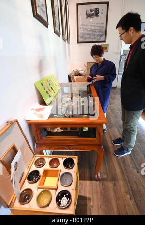 (181031) -- JIANYANG, Oct. 31, 2018 (Xinhua) -- Li Ximei (L), an inheritor of traditional firing techniques of 'Jian Zhan', a kind of black glaze bowl, shows her work of 'Jian Zhan' to a journalist at an exhibition hall in Jianyang, southeast China's Fujiang Province, Oct. 29, 2018. 'Jian Zhan', a kind of temmoku glaze or black glaze porcelain, was then used only by emperors of ancient China's Song Dynasty (960-1279). Famous for its nobility and gorgeousness, 'Jian Zhan' was numerously exported overseas through the Silk Road on the sea. However, after Song Dynasty, those traditional firing tec Stock Photo