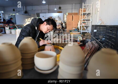 (181031) -- JIANYANG, Oct. 31, 2018 (Xinhua) -- A craftsman polishes the body of a semifinished 'Jian Zhan', a kind of black glaze bowl, at a workshop in Jianyang, southeast China's Fujiang Province, Oct. 29, 2018. 'Jian Zhan', a kind of temmoku glaze or black glaze porcelain, was then used only by emperors of ancient China's Song Dynasty (960-1279). Famous for its nobility and gorgeousness, 'Jian Zhan' was numerously exported overseas through the Silk Road on the sea. However, after Song Dynasty, those traditional firing techniques to make 'Jian Zhan' failed to be handed down to future genera Stock Photo