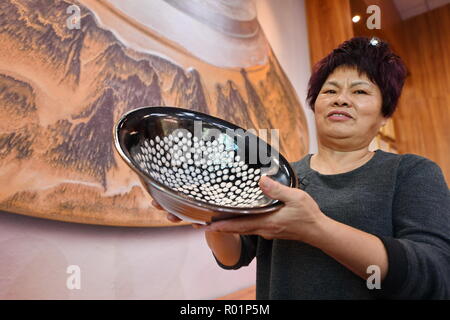(181031) -- JIANYANG, Oct. 31, 2018 (Xinhua) -- Li Ximei, an inheritor of traditional firing techniques of 'Jian Zhan', a kind of black glaze bowl, introduces her work of 'Jian Zhan' in Jianyang, southeast China's Fujiang Province, Oct. 29, 2018. 'Jian Zhan', a kind of temmoku glaze or black glaze porcelain, was then used only by emperors of ancient China's Song Dynasty (960-1279). Famous for its nobility and gorgeousness, 'Jian Zhan' was numerously exported overseas through the Silk Road on the sea. However, after Song Dynasty, those traditional firing techniques to make 'Jian Zhan' failed to Stock Photo