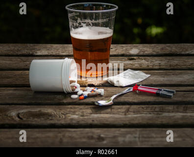 A glass of beer, pills, barbiturates, drugs, cocaine, heroin, a syringe and  a spoon on a table. Drug addiction concept Stock Photo - Alamy