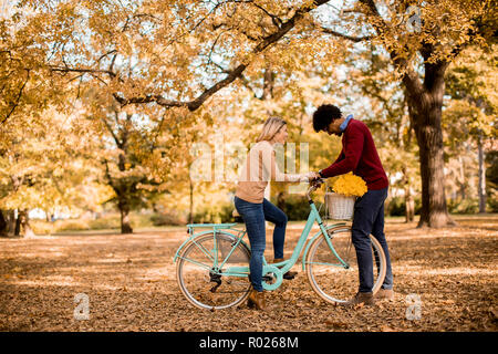 Multiracial couple with bicycle standing in the autumn park Stock Photo