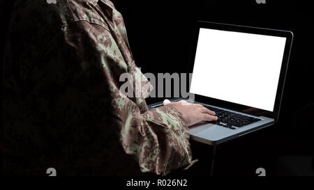 US Army. Young soldier working with a laptop computer with blank screen on black background Stock Photo