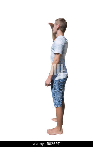 Side view full length portrait of casual young man holding hand to forehead over eyes to protect from sun rays, searching or looking for someone isola Stock Photo