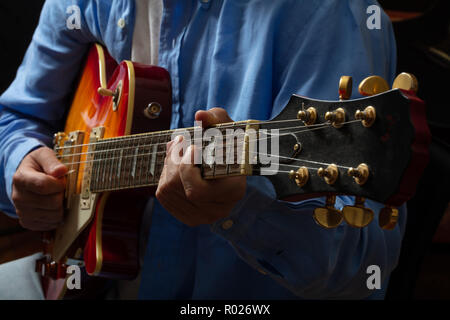 Young man playing electric guitar, close up view, dark background Stock Photo