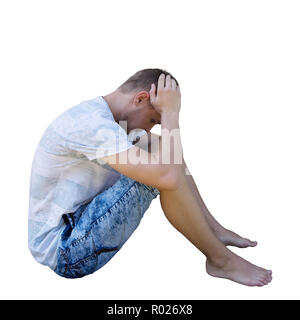 Side view full length portrait of sadl young man sitting on the ground upset looking down and meditate isolated over white background. Stock Photo