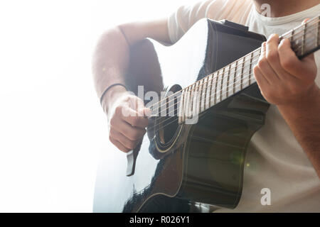 Young man playing guitar, close up view, white background