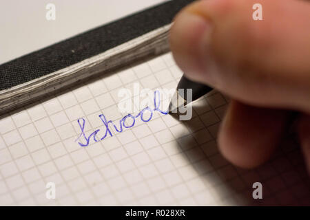 human hand writing school on notepad with ink ball pen Stock Photo