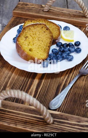 Sliced lemon cake with blueberries on wooden tray. Stock Photo