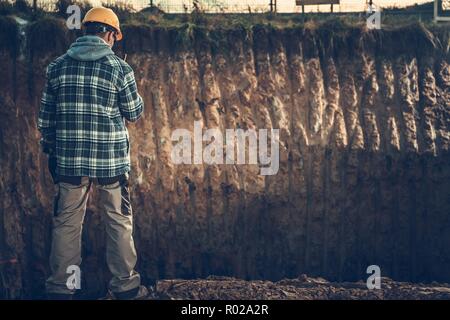 Ground Works Supervisor in Yellow Hard Hat Calling Other Worker Using Walkie Talkie. Construction Site Supervising. Stock Photo