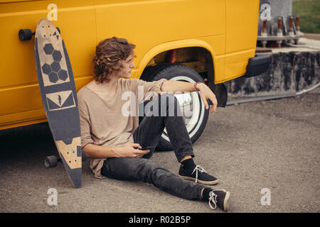 hipster guy sitting next his yellow car during road trip Stock Photo