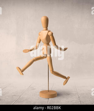 Wooden mannequin posed in front of a greyish background Stock Photo