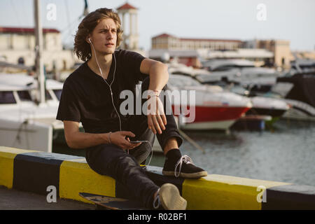 hipster man sitting on longboard using his phone Stock Photo