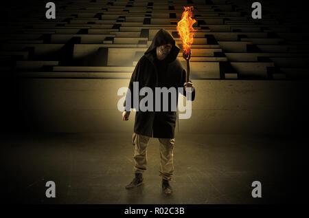 Ugly, aberrant man coming out from the labyrinth with burning flambeau on his hand  Stock Photo