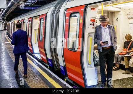 London England,UK,Embankment Underground Station train Tube,subway tube,platform,man men male,passenger passengers rider riders,commuter,train,stopped Stock Photo