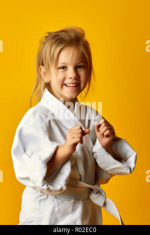 The karate girl on a yellow background with white belt is hitting right hand Stock Photo