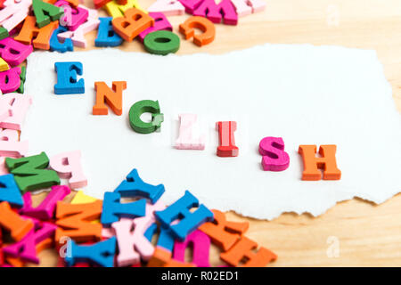 ENGLISH word in wooden letters near a pile of other letters over wood board background Stock Photo