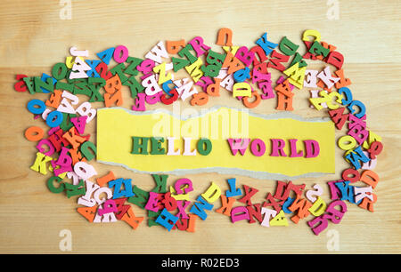 Hello world message in wooden letters near a pile of other letters over wood board background Stock Photo