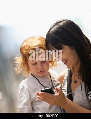 Young woman showing something to her young son on a cell phone. Stock Photo