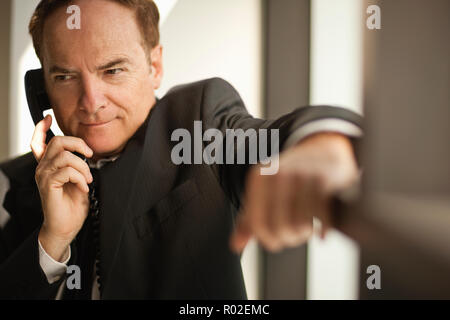Businessman in suit stands listening on the phone. Stock Photo