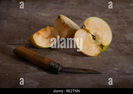 Bramley apple cut in half and slightly oxidising with internal structure fluorescence and unseen colours from blacklight and pigments in wooden board Stock Photo