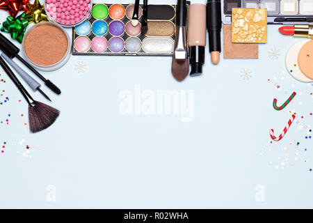 Christmas makeup cosmetics background. Foundation, powder, blusher, color glitter eyeshadow, mascara, eyeliner, lipstick. Bright holiday make-up. Copy Stock Photo