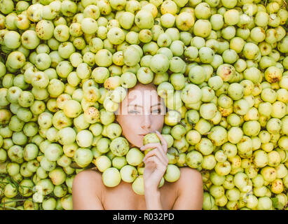 Portrait of beautiful girl that lies in the green apples, apples near the face, kissing apple Stock Photo