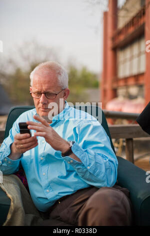 Man sending a text message while sitting in an armchair. Stock Photo