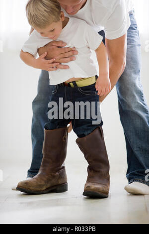 Boy trying on father's cowboy boots Stock Photo