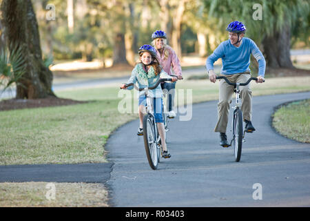 Family cycling along sidewalk Stock Photo