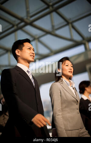 Three business colleagues walking together through an office building. Stock Photo
