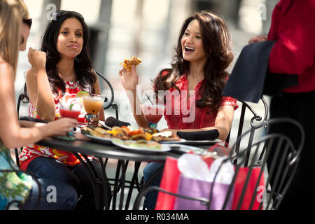 Three smiling friends having lunch at a restaurant. Stock Photo