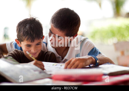 Father helping his son with his homework on a table. Stock Photo
