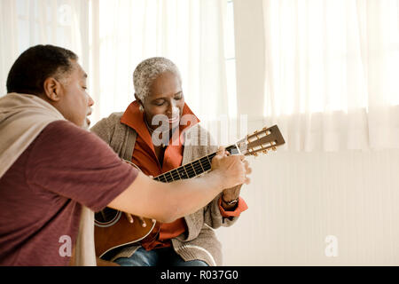 Happy senior man teaching his wife how to play guitar. Stock Photo