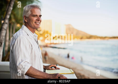 Mature man enjoys the view from the balcony of his hotel. Stock Photo