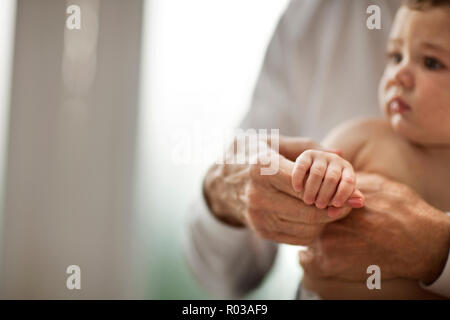 Close up of a baby's hand gripping the finger of her grandmother. Stock Photo