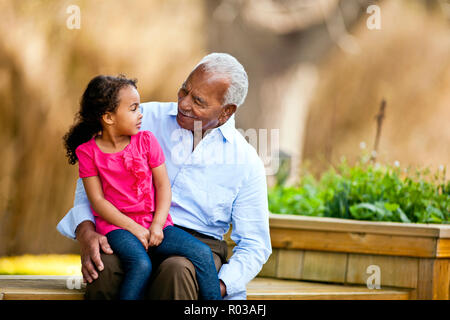 Young girl sitting on her grandfathers knee. Stock Photo