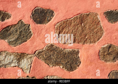 Granite stone boulders interspersed in concrete painted in reddish color Stock Photo