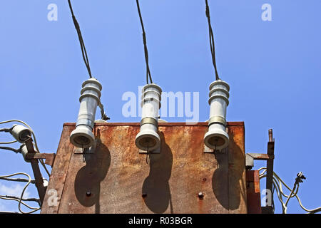 Electric insulators and wires on the old three-phase electrical transformer on a background of blue sky Stock Photo