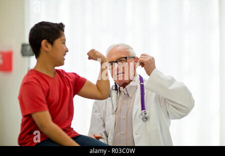 Playful young boy flexing his muscles at a doctor's office. Stock Photo