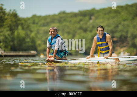 Father and son having fun paddleboarding on the river. Stock Photo