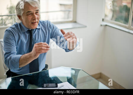 Businessman gesturing during a meeting in a corporate board room. Stock Photo