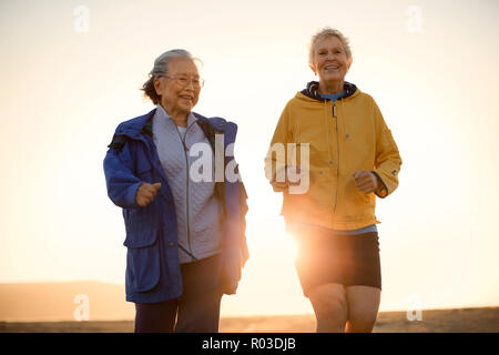 Two senior woman exercising together on the beach. Stock Photo