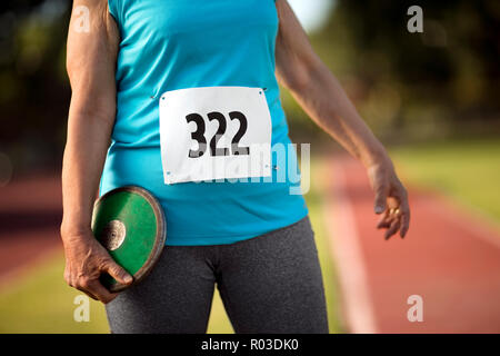 Woman holding a discus on an athletic track. Stock Photo