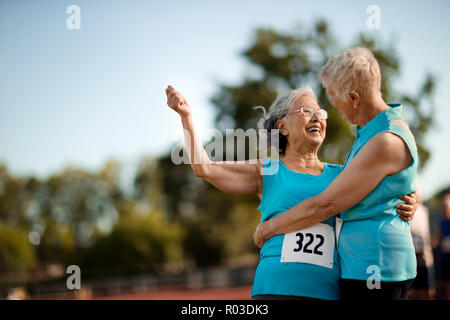 Two happy senior women embracing after competing in an athletic event. Stock Photo