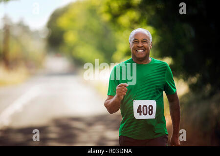 Portrait of a smiling mature man jogging on a rural road. Stock Photo